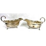 A pair of Edwardian silver sauce boats of typical form each with wavey rim and flying leaf cap