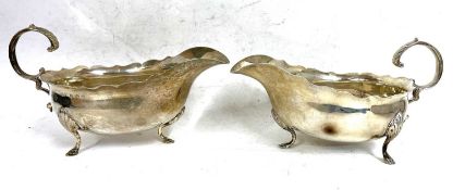 A pair of Edwardian silver sauce boats of typical form each with wavey rim and flying leaf cap