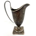 Hallmarked silver cream jug of helmet shape, the foot is a square pedestal form having a loop reeded