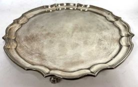 Hallmarked silver salver of plain circular form with pie crust border supported on three scroll