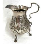 George III silver cream jug having a wavy rim, the body features later embossed and chased encanthus