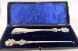 A cased Edwardian part set to include long handled button hook and shoe horn, silver handles