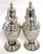 A pair of Victorian silver peppers, the urn shaped bodies with a wrythen design having urn finials