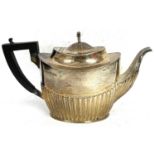 A hallmarked silver teapot of oval form, half fluted body and hinged urn finial lid, ebonised
