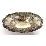 An Edwardian silver dish of shallow oval form having an embossed edge with scrolls and flowers and a