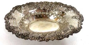 An Edwardian silver dish of shallow oval form having an embossed edge with scrolls and flowers and a