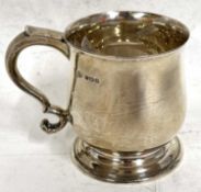 A George V small silver tankard of plain baluster form, looped handle and raised on a spreading