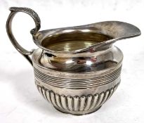 George V silver cream jug of circular form with reeded and half fluted body design, leaf capped