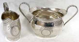 An Edwardian silver twin handled sugar bowl of oval form with engraved and wriggle work decoration