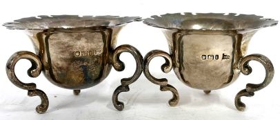 A pair of Edward VII open silver salts of cauldron form with serated edges, supported on three