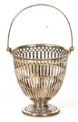 A George V silver swing handled pierced basket with a geometric pattern and beaded decoration, a