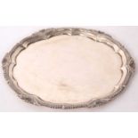 A George V silver salver, of shaped circular form with raised gadrooned rim and a shall border,