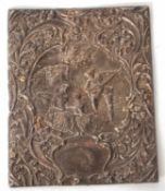 A hallmarked silver book cover, elaborately embossed with figures beneath an arbor and scrolls and