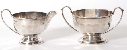 A George V silver twin handle sugar bowl and matching cream jug of circular form with panelled