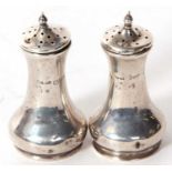 A pair of George V silver peppers of plain tapering cylindrical form, pull off pierced lids, Chester