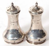 A pair of George V silver peppers of plain tapering cylindrical form, pull off pierced lids, Chester