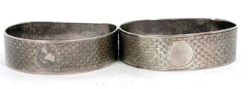 Two hallmarked silver D shaped serviette rings, engine turned decoration around a circular