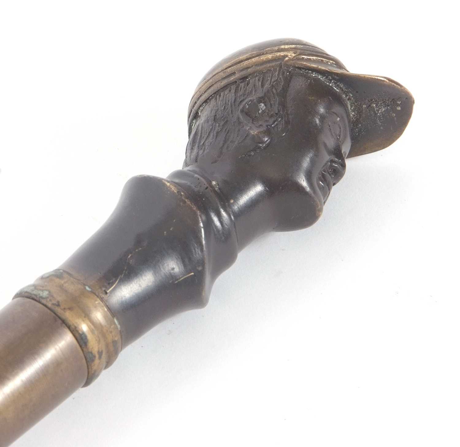 Vintage walking stick/cane with a weighted brass jockeys head on a later wooden shaft (a/f)