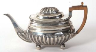 A George III teapot with a part lobed body with applied gadrooned border and wooden handle supported