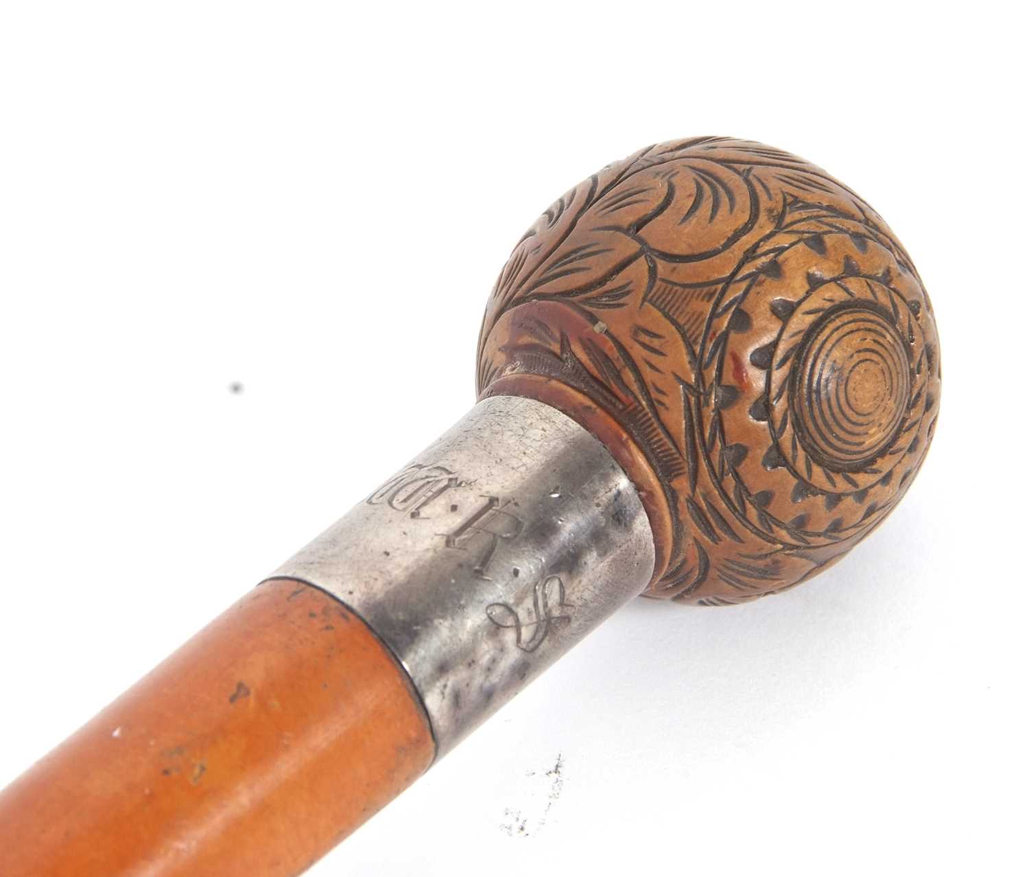 An antique walking stick with ball finial, carved with foliate and geometric designs with a metal
