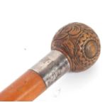 An antique walking stick with ball finial, carved with foliate and geometric designs with a metal