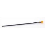 A vintage ebonised walking stick with an amber coloured resin ball finial