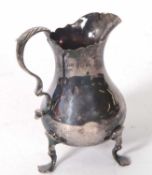 A late Victorian silver cream jug of plain form with round bellied body, scroll handle with leaf