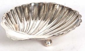 George V silver shell shaped dish supported on three ball feet, 12cm long, 63gms