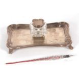 A late Victorian silver ink stand of shaped rectangular form, having reeded edges and supported on