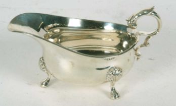 A George V silver sauce boat of typical form having reeded rim and flying leaf capped handle,