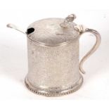 A Victorian silver mustard pot of drum form, elaborately chased and engraved with flowers and