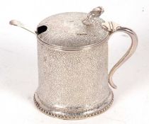 A Victorian silver mustard pot of drum form, elaborately chased and engraved with flowers and