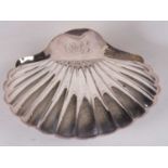 Large silver shell shaped dish, the handle engraved with initials, supported on three fluted ball