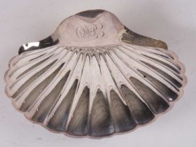 Large silver shell shaped dish, the handle engraved with initials, supported on three fluted ball