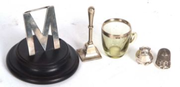 Mixed Lot: An Edwardian silver menu holder in the form of the letter "M" on a black ebonised sockel,