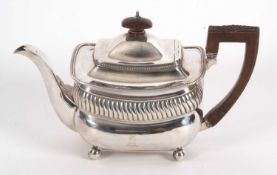A George III silver teapot of oval form having gadrooned rims with part fluted decoration to the