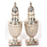 Pair of Victorian silver peppers of urn shape on square bases with fluted wrythen bodies, screw on