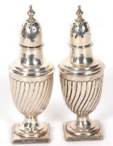 Pair of Victorian silver peppers of urn shape on square bases with fluted wrythen bodies, screw on