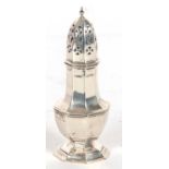 An Edwardian silver caster of octagonal form, pull off pierced lid with urn finial, standing on a