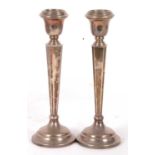 A pair of silver loaded candlesticks having tapering and cantered square columns with stepped bases,