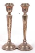 A pair of silver loaded candlesticks having tapering and cantered square columns with stepped bases,
