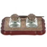 An Elizabeth II silver mounted twin bottle ink stand, the treen base with silver embossed frame