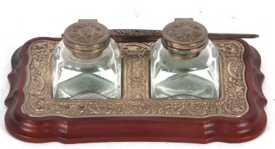 An Elizabeth II silver mounted twin bottle ink stand, the treen base with silver embossed frame