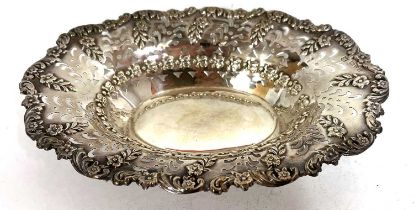 An Edwardian silver dish of shallow oval form having an embossed edge with scrolls and flowers and a