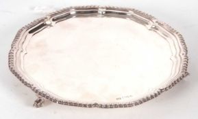A silver salver having an applied shaped gadrooned border, a plain ground, supported on three cast