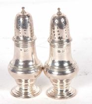 Pair of silver casters of baluster form reeded bodies with pull off pierced lids, London 1913,