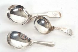 A group of three silver caddy spoons, a small George III example, fiddle pattern having a circular