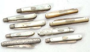 A group of eight mother of pearl handle fruit folding knives with hallmarked silver blades,