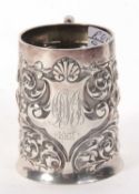 A late Victorian silver mug, a slight tapering cylindrical form, elaborately embossed with scrolls