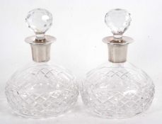 A pair of heavy cut glass decanters of slight depressed circular form having silver collars and